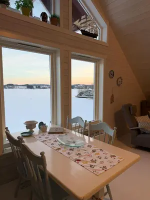 a dining room with a table and two windows at Cabin by the lake in Sveio