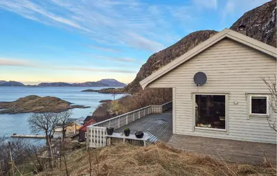 a white house with a deck next to the water at 3 Bedroom Stunning Home In Tansøy in Tansøy