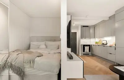 a white bedroom with a bed and a kitchen at Modern and cozy apartment ONLY 5 minutes from City Center in Bergen