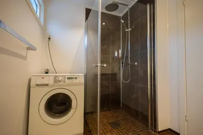 a bathroom with a shower and a washing machine at Spacious Apartment - City Center in Stryn