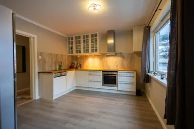 a kitchen with white cabinets and wooden floors and a window at Spacious Apartment - City Center in Stryn