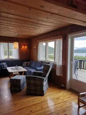 a living room with a couch and a table and windows at Åsrud seter i Jotunheimen in Vaga