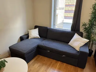 a blue couch in a living room with a window at Cozy Studio in Lademoen, Trondheim in Trondheim