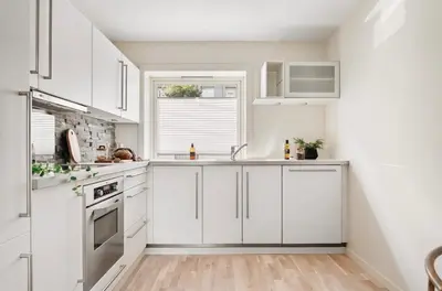 a white kitchen with white cabinets and a window at Central modern apartment in Bergen in Bergen