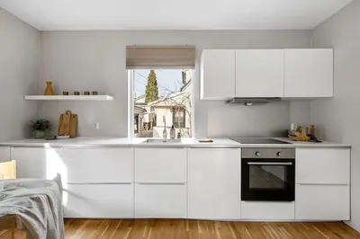 a white kitchen with white cabinets and a window at Cozy Apartment near City Centre in Bergen