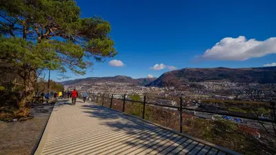 a person walking down a sidewalk with a view of a city at Cozy Apartment near City Centre in Bergen