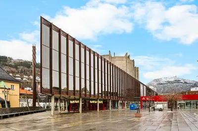 a building on a street with a mountain in the background at City Center, Light & Modern Apartment in Bergen