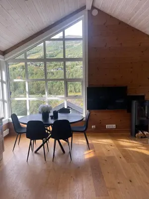 a dining room with a table and chairs and a large window at Velkommen til topp leilighet på Strandafjellet 2 soverom og hems in Stranda