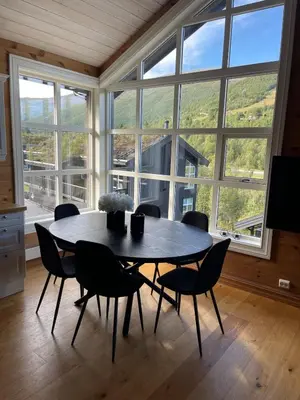 a table and chairs in a room with a large window at Velkommen til topp leilighet på Strandafjellet 2 soverom og hems in Stranda