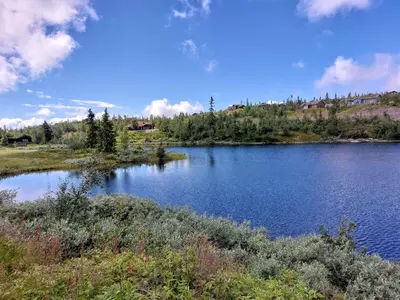 a view of a lake with a house in the background at Log cabin in Valdres Fireplace Sauna 1000 m above sea level in Aurdal