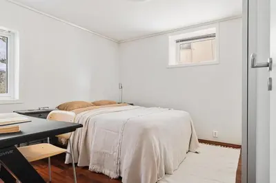 a white bedroom with a bed and a desk at Bright and cozy 2-bedroom apartment in Bergen