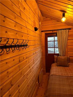 a bedroom with a wooden wall in a cabin at Norsk laftehytte Filefjell I 123 kvm I10 sengeplasser I 2 stuer in Borgund