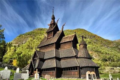 a large wooden building with a mountain in the background at Norsk laftehytte Filefjell I 123 kvm I10 sengeplasser I 2 stuer in Borgund