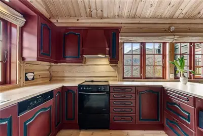 a kitchen with red cabinets and a black stove at Norsk laftehytte Filefjell I 123 kvm I10 sengeplasser I 2 stuer in Borgund