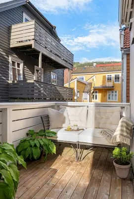 a balcony with a white couch on a wooden deck at Modern and airy apartment in Bergen city center in Bergen