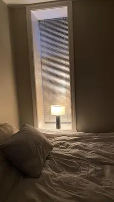 a bedroom with a bed and a window with a lamp at Central and cozy apartment in Bergen City Center in Bergen