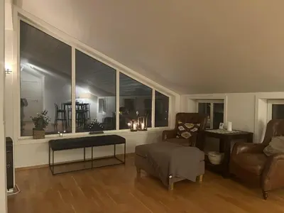 a living room with a couch and chairs and a large window at Romslig toppleilighet 134 kvm med balkong perfekt for firma og grupper in Beitostøl