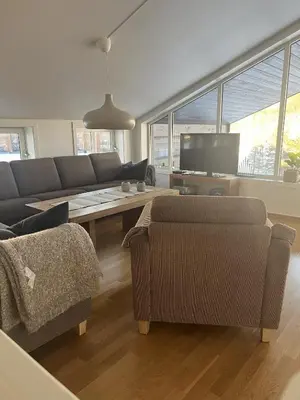 a living room with a couch and a table at Romslig toppleilighet 134 kvm med balkong perfekt for firma og grupper in Beitostøl