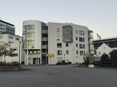 a large white building in a parking lot at Modern apartment in central Bergen in Bergen
