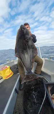 a man sitting on a boat with a large fish at Sunset Cabin in Ålesund