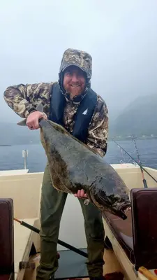 a man holding a large fish in a boat at Sunset Cabin in Ålesund
