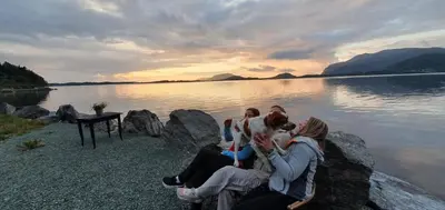 a group of people sitting on rocks near a body of water at Sunset Cabin in Ålesund