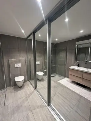 a bathroom with two toilets and a shower and a sink at Stor og moderne leilighet ved råstølen bybanestopp in Bergen