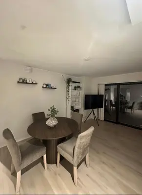 a living room with a table and chairs and a television at Stor og moderne leilighet ved råstølen bybanestopp in Bergen