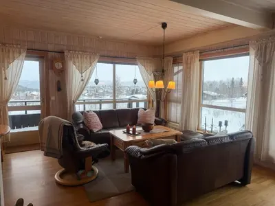 a living room with leather furniture and a large window at Koselig Leilighet Med Flott Utsikt in Beitostøl