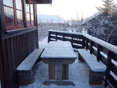 a wooden picnic table covered in snow next to a window at Familievennlig Hytte Rett Ved Sentrum in Beitostøl