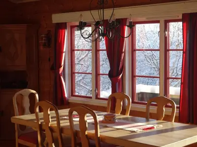 a dining room with a table and chairs and windows at Familievennlig Hytte Rett Ved Sentrum in Beitostøl