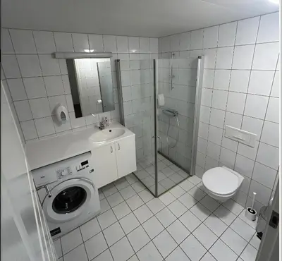 a white tiled bathroom with a toilet and a shower at Familievennlig Leilighet Med 7 Sengeplasser in Beitostøl