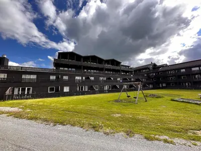 a building with a grassy field in front of a building at 3-Roms Leilighet Nær Alle Beitostølens Fasiliteter in Beitostøl