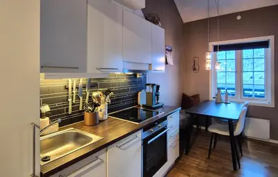 a kitchen with white cabinets and a sink and a table at 2 Bedroom Cozy Apartment In Røldal in Røldal