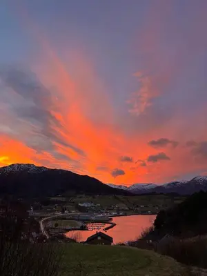 a sunset over a body of water with mountains at Leilighet i paradisbukta in Torvikbukt