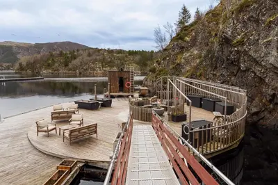 a wooden deck with chairs and tables on a body of water at Kuringen Brygge Hotel and Restaurant in Refsnes