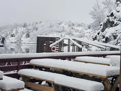 a group of benches covered in snow next to a lake at Kuringen Brygge Hotel and Restaurant in Refsnes