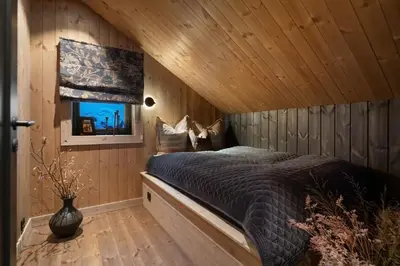 a bedroom with a bed in a wooden cabin at FJELLRO Private Alpine Lodge Høgevarde in Flå