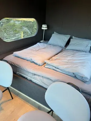 a bed in a room with two chairs and a window at Langelandsvik Gard Birdbox