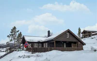 a log cabin in the snow with a flag at Stunning Home In Bjorli With Sauna in Bjorli