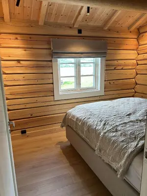 a bedroom with wooden walls and a bed with a window at Gunhild-stugu