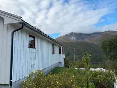 a white building with mountains in the background at Holiday Home Stabben white House by Interhome in Aure