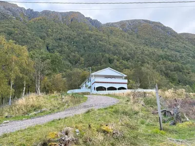 a building on a dirt road in front of a mountain at Holiday Home Stabben white House by Interhome in Aure
