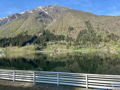 a reflection of a mountain in a lake with a fence at Holiday Home Fjordtraum by Interhome in Balestrand