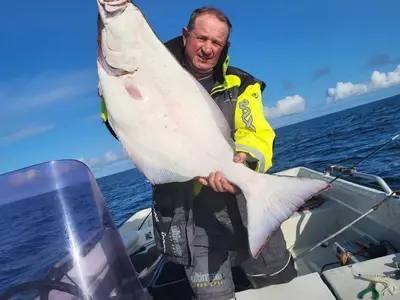 a man holding a large fish in a boat at Holiday Home Stabben Blue House by Interhome in Storsæter