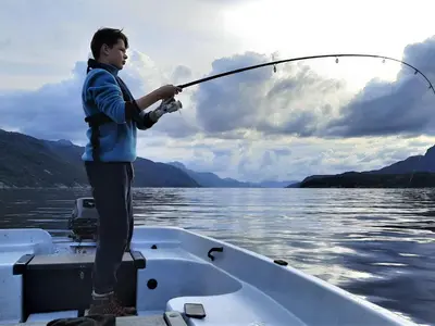 a man standing on a boat holding a fishing rod at Holiday Home Ein Traumstandort by Interhome in Hebnes