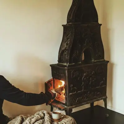 a person is putting food into an old stove at Romantic Getaway Hot Tub, Cinema & View in Stange