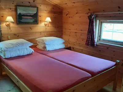 a bedroom with two beds in a log cabin at Holiday Home Häuschen mit Blick auf das Wasser by Interhome in Ropeid