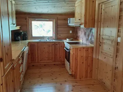 a kitchen with wooden cabinets and a sink and a window at Holiday Home Häuschen mit Blick auf das Wasser by Interhome in Ropeid