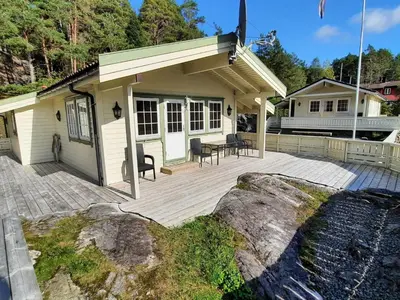 a house with a wooden deck with a building at Holiday Home Häuschen mit Blick auf das Wasser by Interhome in Ropeid
